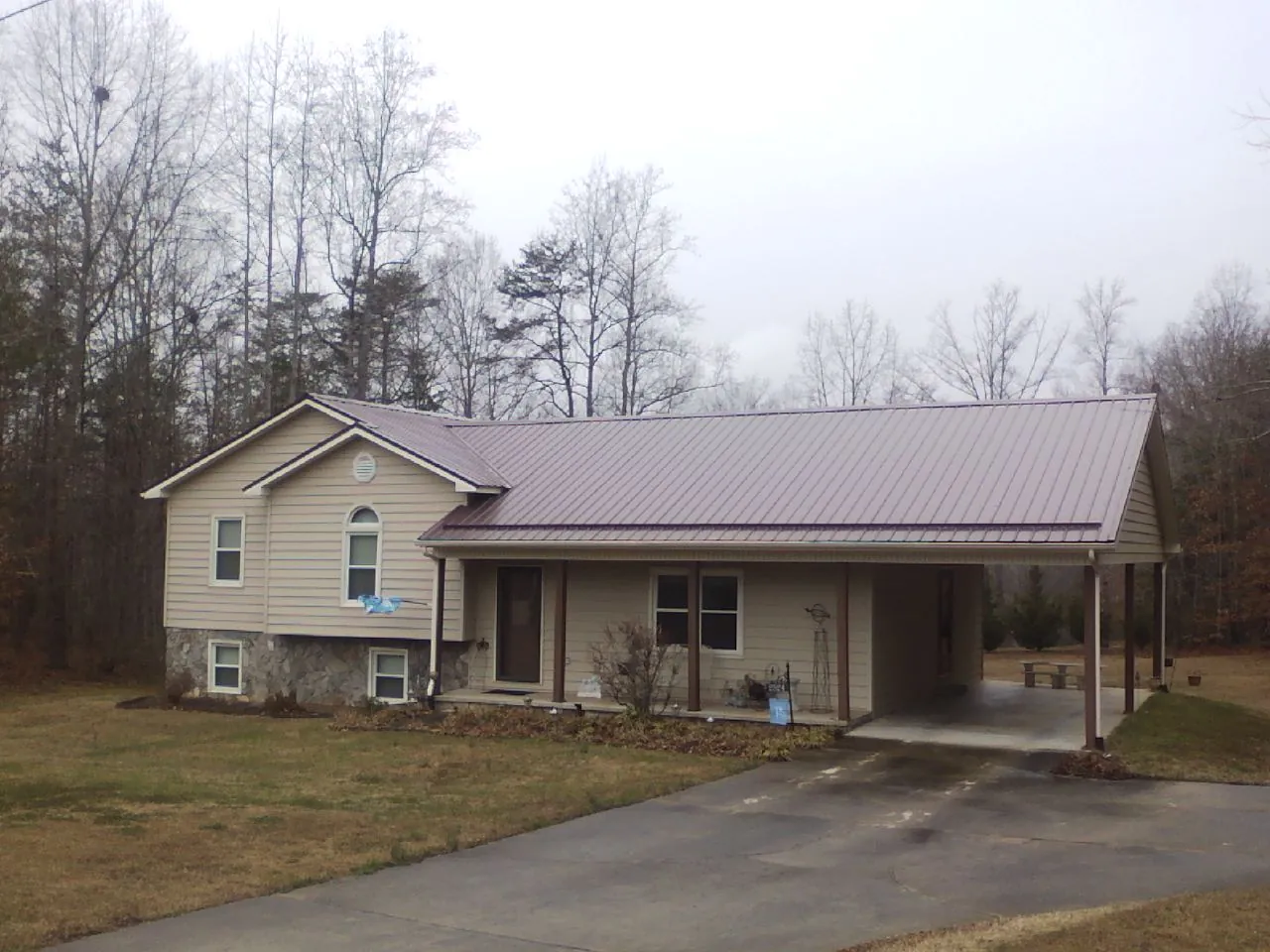 Burgundy metal roof on a tan split level home with an attached carport in Moravia
