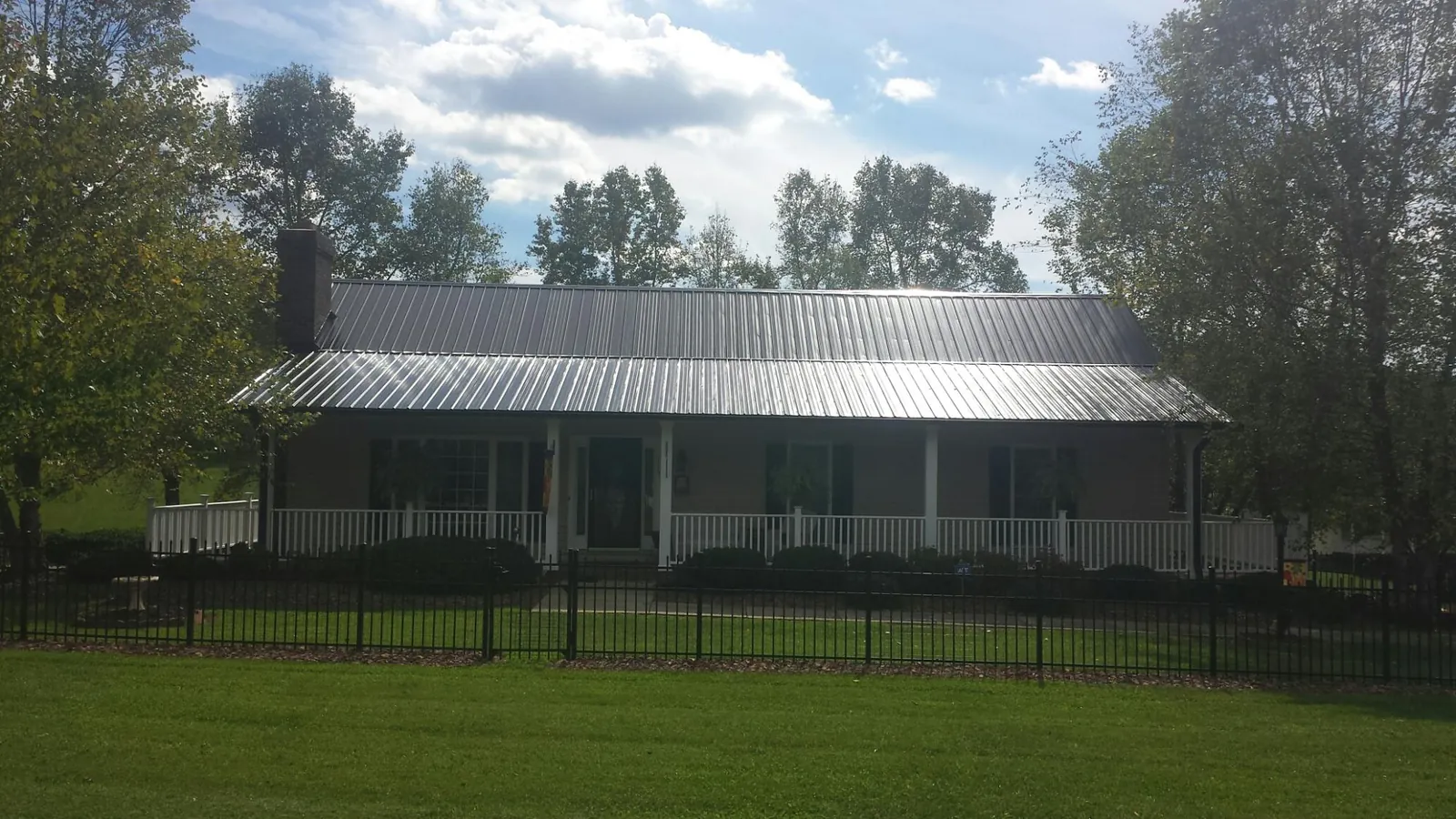 Gray metal roof on a brick ranch with a full width front porch — Gutter Guard Installation work by our crew in Moravia