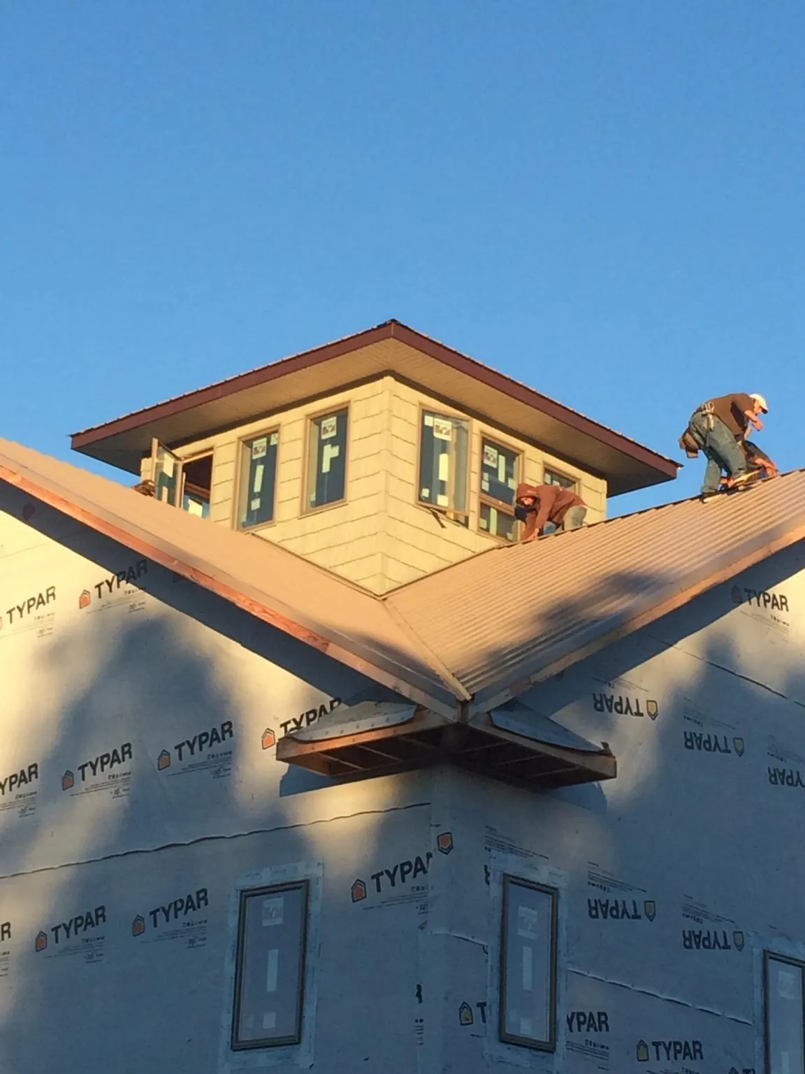 Roofers working around a rooftop cupola on a new metal roof at sunset — Roof Waterproofing in Moravia by Roofing Brothers